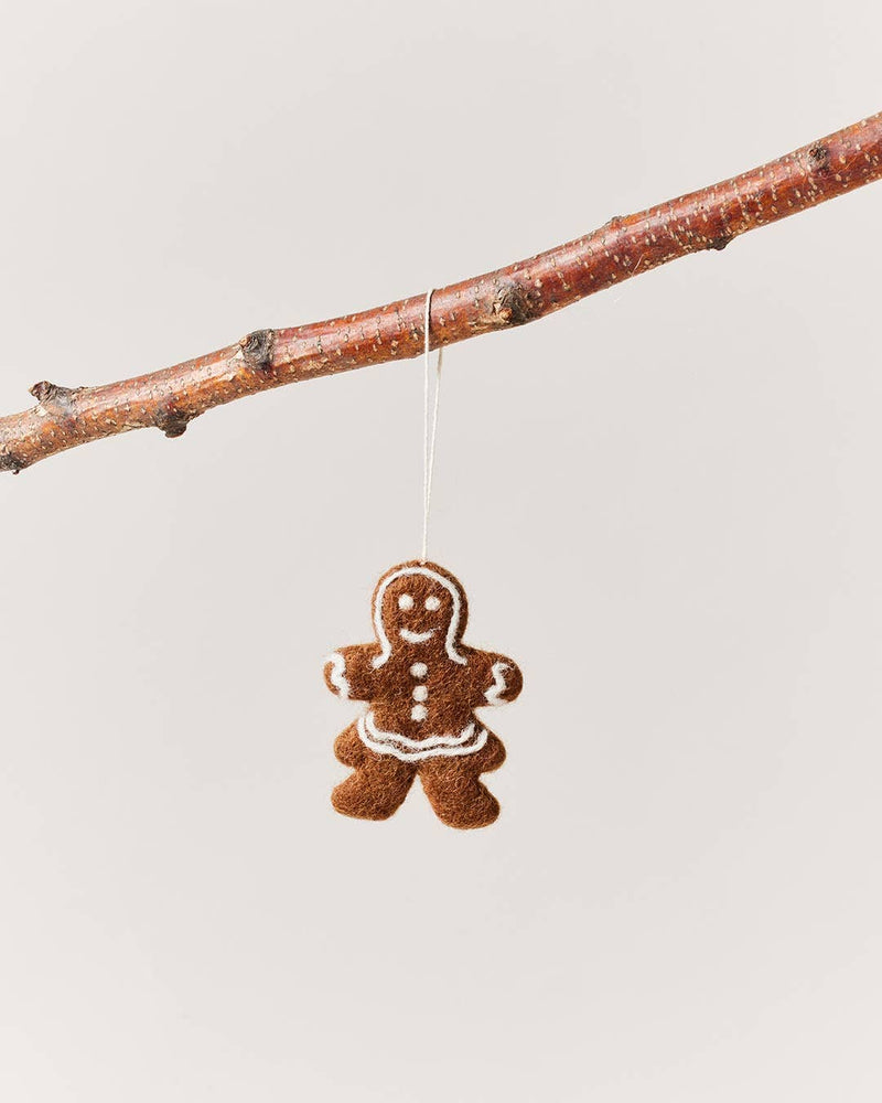 Farmhouse Pottery - Felted Gingerbread Ornament: Gentleman, handcrafted from 100% wool, hangs from a twig, showcasing fair trade craftsmanship with white icing-style trim.