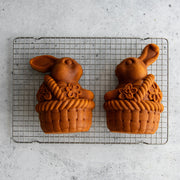 Nordic Ware | Bunny In Basket 3D Cake Pan showcasing two bunny-shaped cakes on a cooling rack, highlighting its baking precision and decorative potential for Easter.
