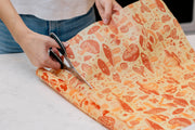 Bee's Wrap - Cut-to-Size Roll - Mushroom Magic in use, featuring a person cutting the mushroom-illustrated wrap on a countertop for a customizable, plastic-free kitchen solution.
