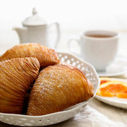 Nicola's Marketplace | Individual Mini Italian Sfogliatelle Pastries in a lacy ceramic bowl, showcasing layered pastry with ricotta and orange peel, dusted with powdered sugar.