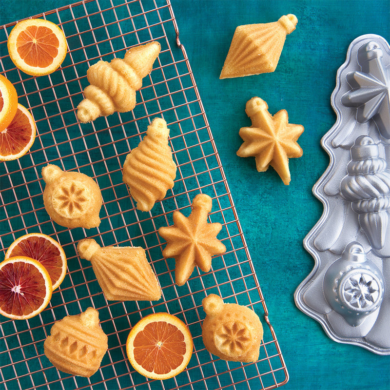 Nordic Ware | Vintage Ornament Cakelet Pan displayed with cookies and orange slices, illustrating its use for festive, detailed holiday baking creations.