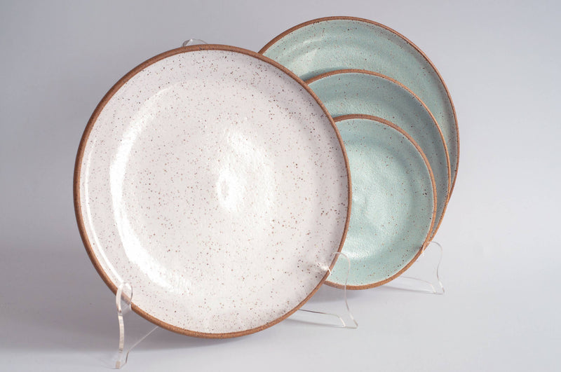 RachaelPots - Dinner Plate: Nude/White displayed on stands, featuring creamy white and mint-green surfaces with earthy-brown rims, hand-thrown stoneware, microwave and dishwasher safe.