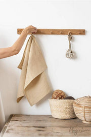 Hand holding a MagicLinen tea towel on a hook, showcasing its hanging loop and high-quality European linen fabric, perfect for kitchen tasks.