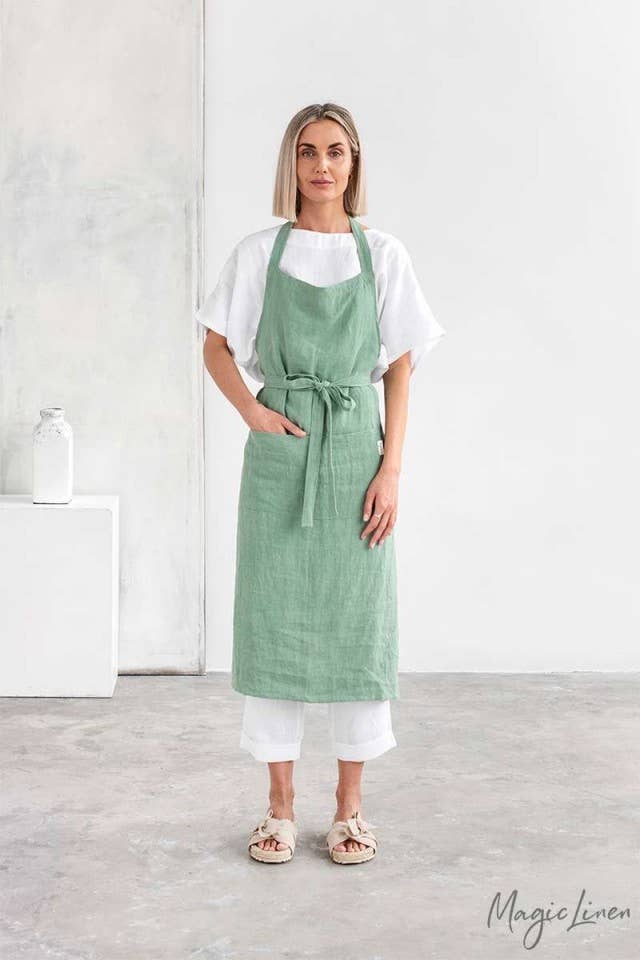 Woman wearing MagicLinen Charcoal Grey Linen Bib Apron with Pockets, ideal for cooking and gardening. Durable and stylish, enhancing culinary experiences.