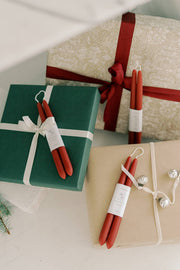 Mo&Co Home - Berry Red Dipped Beeswax Taper Candles atop wrapped gifts, showcasing elegant, handcrafted design with eco-conscious materials. Perfect for special occasions.