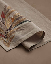 Coral & Tusk - Wheat Harvest Dinner Napkin featuring embroidered feathers and wheat on light-tan linen, perfect for a fall table setting. Measures 20 × 20.