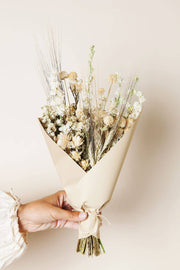 Idlewild Floral Co. - Sage Small Field Bouquet held in hand, showcasing creamy dried flowers and grasses wrapped in kraft paper, perfect for a 4-6 vase.