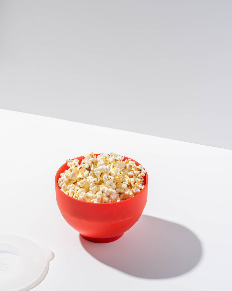 Red silicone W&P Standard Size Popcorn Popper filled with popcorn, designed for microwave use, reusable and collapsible for easy storage.