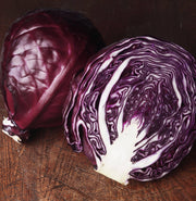 Bentley Seed Co. - Cabbage-Red Acre 1860: Two red cabbages on wood, one whole, one halved, showcasing tight leaves; ideal for vibrant, nutritious meals.