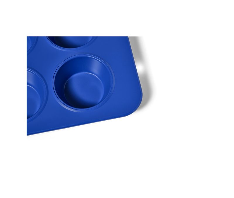 Great Jones | Stud Muffin - Blueberry: Close-up of a nonstick, nontoxic muffin pan by Athens Cooks, featuring four holes for even heat distribution and easy cleanup.