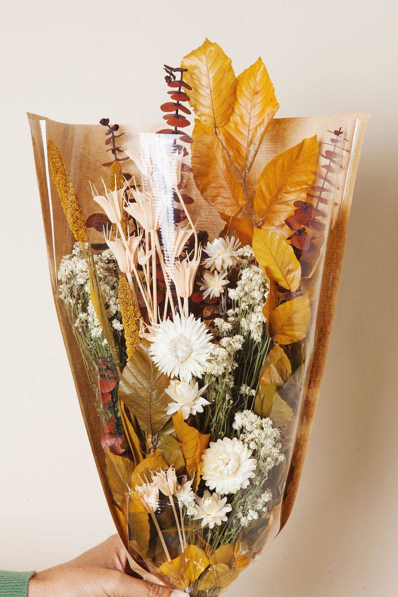 Idlewild Floral Co. - Golden Fall Market Bouquet: Hand-held dried floral arrangement with strawflowers, baby’s-breath, golden grasses, broad leaves, eucalyptus, wrapped in clear cellophane.