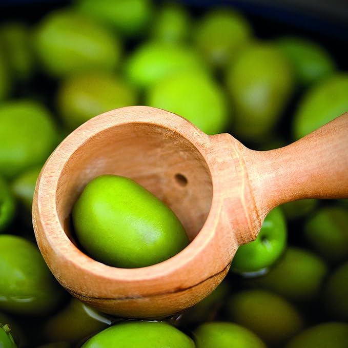 Berard Olivewood Olive Spoon in a bowl of olives, showcasing its elegant design with a long handle and round scoop with draining holes.