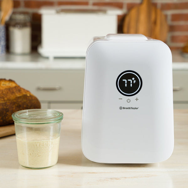 Brod & Taylor SH-100 Sourdough Home toaster beside a jar of butter and a glass of bread, highlighting its sleek design for modern kitchen use.