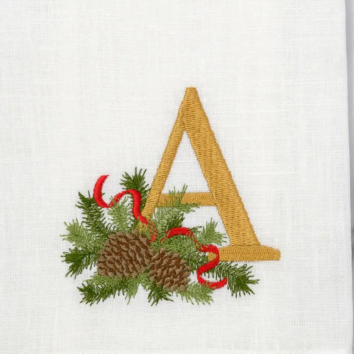 Arte Italica & Crown Linen Designs Winter Pine Monogram Towel, A, White (Multi) featuring a gold A, green pine sprigs, and red ribbon embroidery, showcasing festive elegance.