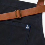 Hedley & Bennett | Essential Waxed Canvas Aprons - Montana, featuring a durable design with an adjustable leather neck strap, navy waist tie, and multiple pockets.