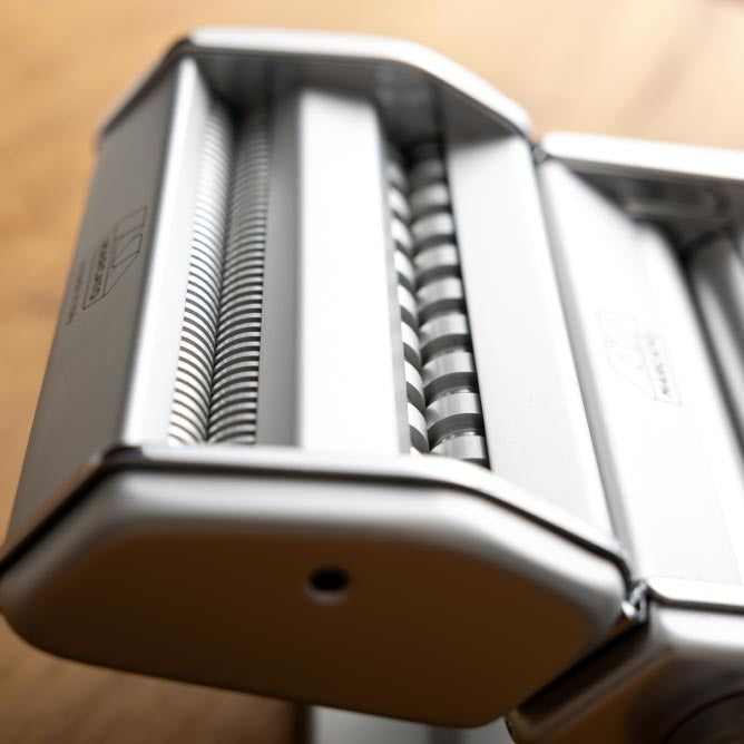 Close-up of the Marcato Atlas 150 Pasta Maker, showcasing its manual controls and pasta cutting features, ideal for crafting homemade Italian pasta.