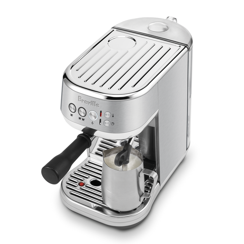 Breville Bambino Plus espresso machine frothing milk with steam wand, showcasing control buttons and portafilter, ideal for precise coffee making at Athens Cooks.