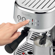 Breville | Bambino Plus espresso machine frothing milk with steam wand; portafilter visible. Ideal for precise coffee making and latte art, available at Athens Cooks.