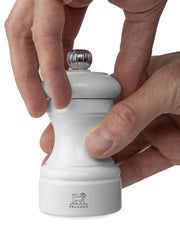 Hands twist the top of a Peugeot | Bistro Salt Mill, Pearl Grey, showcasing its hourglass shape and chrome-topped adjustment knob, ideal for creating a stylish kitchen ambiance.