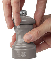 Peugeot | Bistro Pepper Mill, Smoked Grey, shown being used to grind spices, with adjustable grind feature.