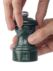 Peugeot | Bistro Pepper Mill, Forest Green, shown being twisted by two hands, highlighting its adjustable grind size feature. Crafted from sustainably sourced wood, ideal for fine dining.