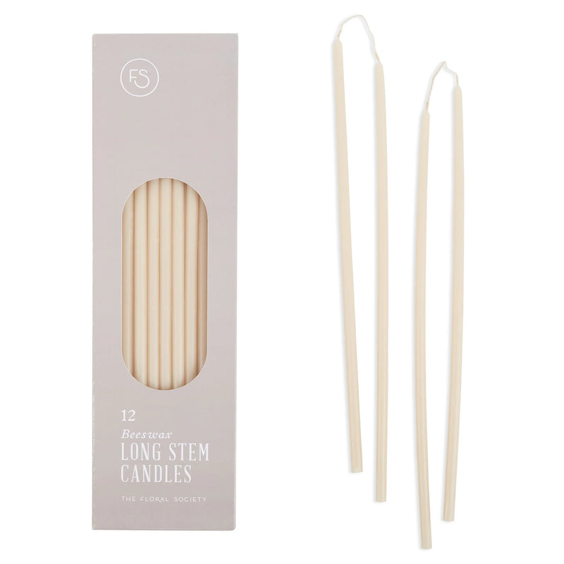 Boxed set of 12 long-stem beeswax candles by The Floral Society, with a few taper candles displayed. Ideal for intimate gatherings, crafted from all-natural beeswax.