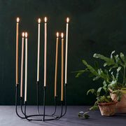 The Floral Society | Long Stem Beeswax Candles, Blossom, lit in a black candelabra, set on a dark tablecloth with houseplants, creating a warm, minimalist ambiance.
