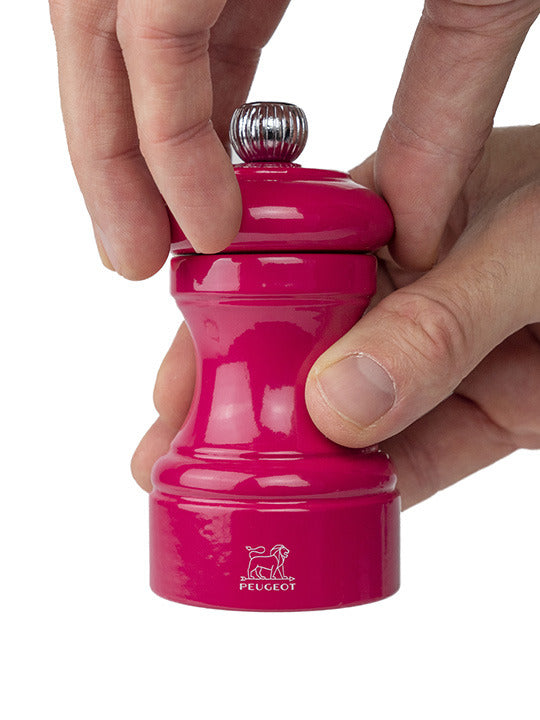 Peugeot | Bistro Pepper Mill, Candy Pink, shown in hands twisting the top knob, featuring a lifetime-guaranteed grinding mechanism. Perfect for enhancing culinary experiences from Athens Cooks.