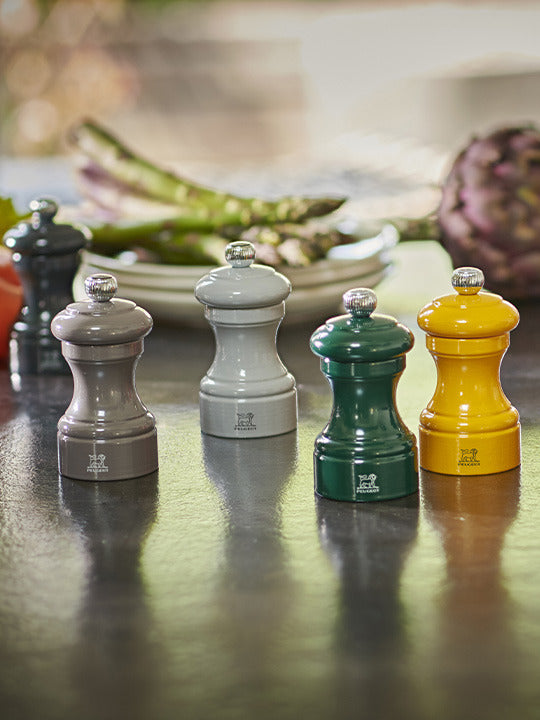 Peugeot | Bistro Pepper Mill, Smoked Grey, on display with other spice grinders, showcasing its adjustable grinding mechanism and sustainable beechwood craftsmanship.