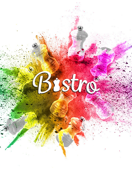 Peugeot | Bistro Pepper Mill 4 Inches, Slate Grey, surrounded by colorful spice bursts, showcasing its timeless design and adjustable grinding feature.