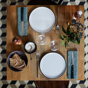 Opinel | Bon Appétit No.125 Steak & Table Knives Sets, Pro displayed on a wooden table, highlighting the black-handled knives atop green linen napkins in an elegant dining setup.