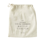 Sir|Madam Brass Bottle Coaster packaging pouch, featuring brand and product description, made of natural-colored cloth with a drawstring, emphasizing vintage-inspired barware elegance.