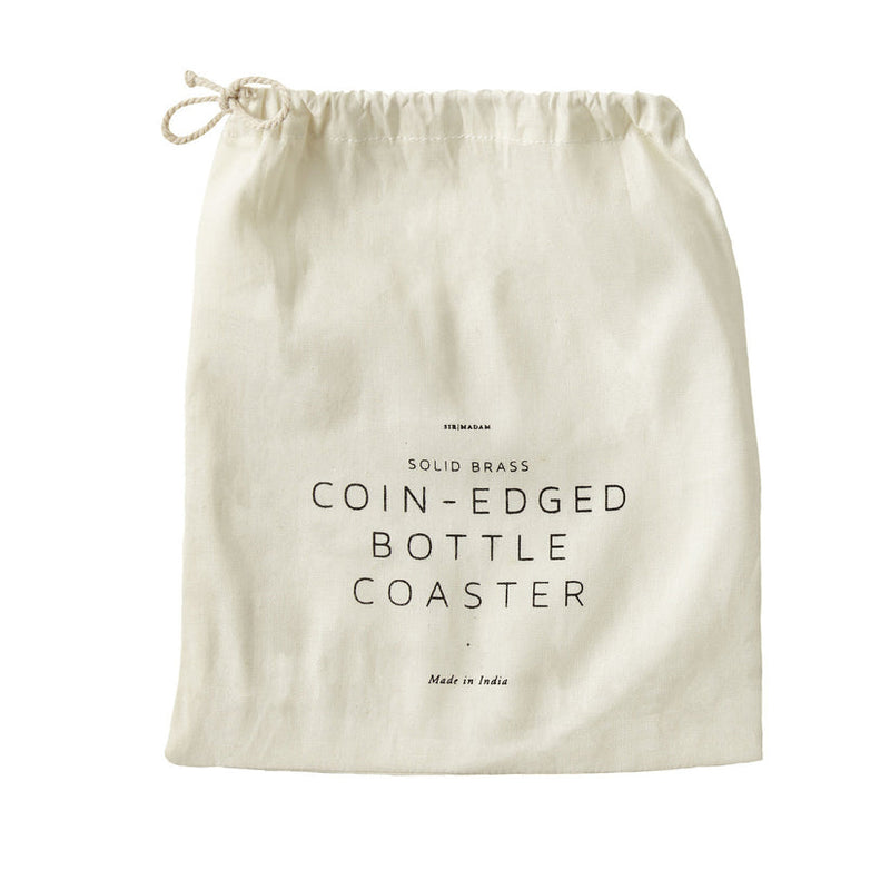 Sir|Madam Brass Bottle Coaster packaging pouch, featuring brand and product description, made of natural-colored cloth with a drawstring, emphasizing vintage-inspired barware elegance.