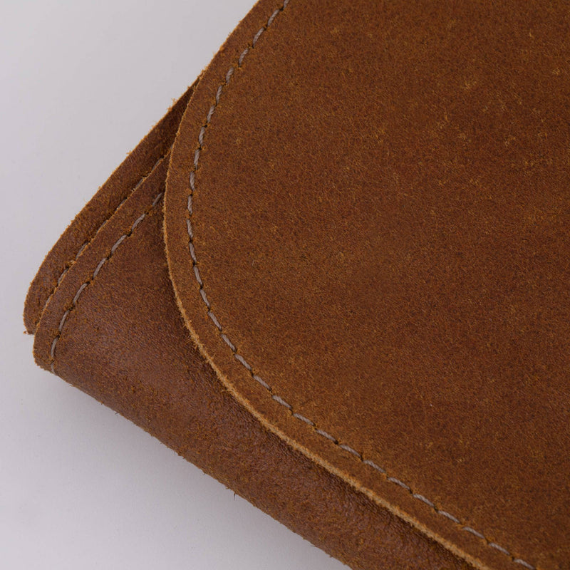 Close-up of the Messermeister Vintage Leather 7 Pocket Knife Roll in amber, highlighting its suede-finished leather and stitched edge, showcasing craftsmanship and quality.