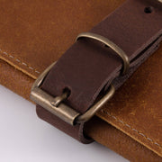 Close-up of the Messermeister Vintage Leather 7 Pocket Knife Roll's brown leather strap with a brass buckle, highlighting its craftsmanship and durability.