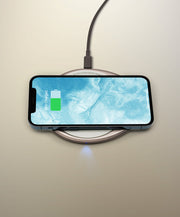 OHOM | Ui 3 Self-heating Mug Set: Moonmist Blue, displayed charging a smartphone on a wireless pad, showcasing its dual function as a mug warmer and phone charger.