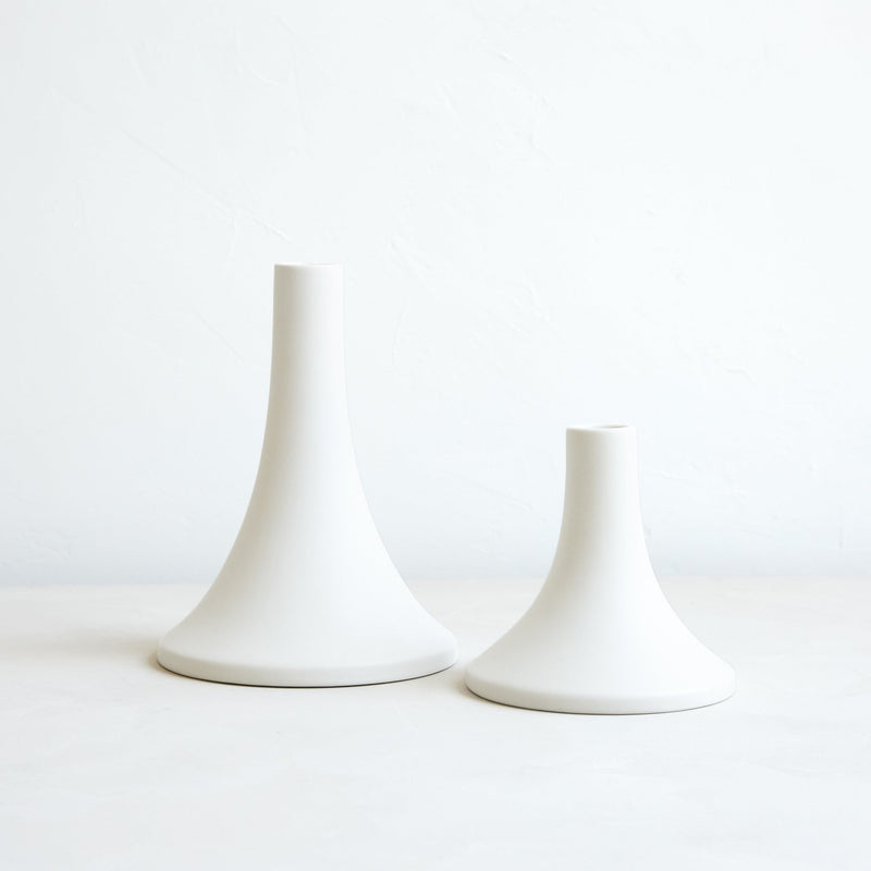 The Floral Society | Candle Holders, Grand, Matte White Tall: Two elegant, flared-base ceramic holders in varied heights, designed for standard taper candles, offering a sleek, handcrafted finish.