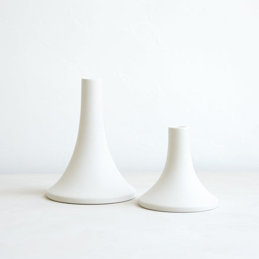 The Floral Society | Candle Holders, Grand, Matte White Tall: Two elegant, flared-base ceramic holders in varied heights, designed for standard taper candles, offering a sleek, handcrafted finish.