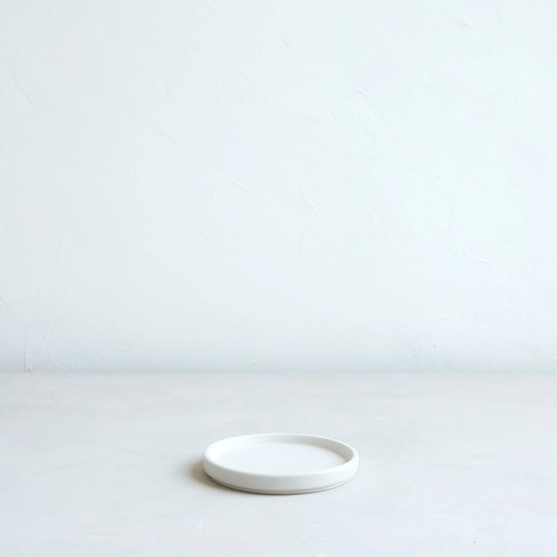 The Floral Society's Daily Plate, Matte White, sits centered, showcasing its wide, stable base, perfect for candles or as a versatile kitchen accessory.