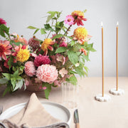 The Floral Society | Long Stem Beeswax Candles, Ochre, elegantly lit on a table with garden-style flowers, ceramic plate, and glass tumbler, ideal for intimate gatherings.