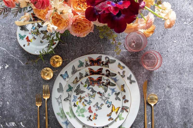 Vista Alegre | Lacroix Butterfly Parade Dinner Plate on a table with floral accents, showcasing a three-dimensional butterfly design in a curated kitchen setting.