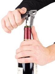 Hands using the Peugeot Clavelin Sommelier Corkscrew, Black, to effortlessly extract a cork from a wine bottle, showcasing its superior design and functionality.