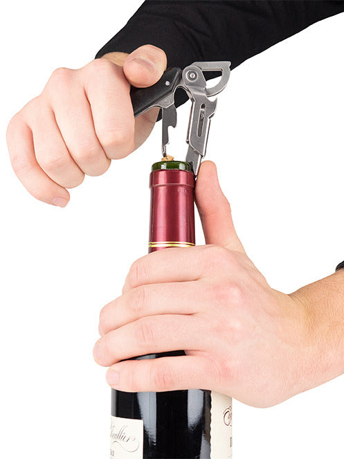 Hands using the Peugeot Clavelin Sommelier Corkscrew, Black, to effortlessly extract a cork from a wine bottle, showcasing its superior design and functionality.