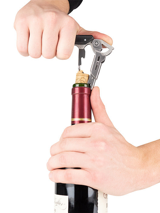 Hands using the Peugeot Clavelin Sommelier Corkscrew, Black, effortlessly extracting a cork from a wine bottle, showcasing its patented design for seamless performance.