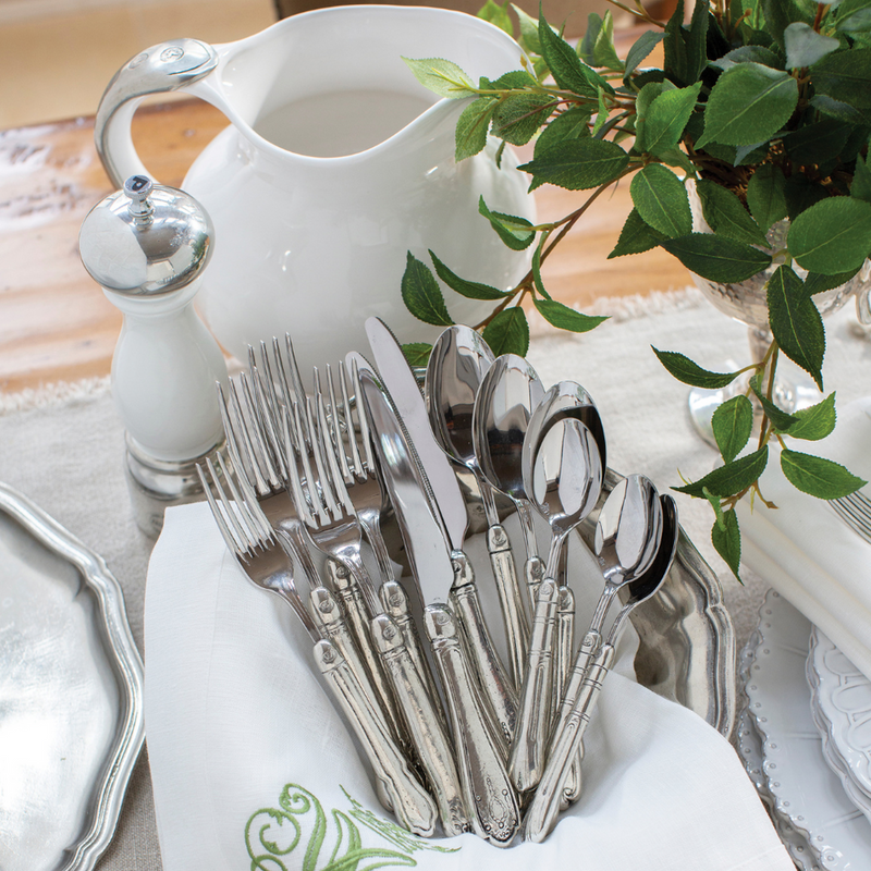 Arte Italica & Crown Linen Designs Hotel 5-Piece Placesetting displayed on a wooden table with silver-plated cutlery, a ceramic pitcher, and a white grinder.