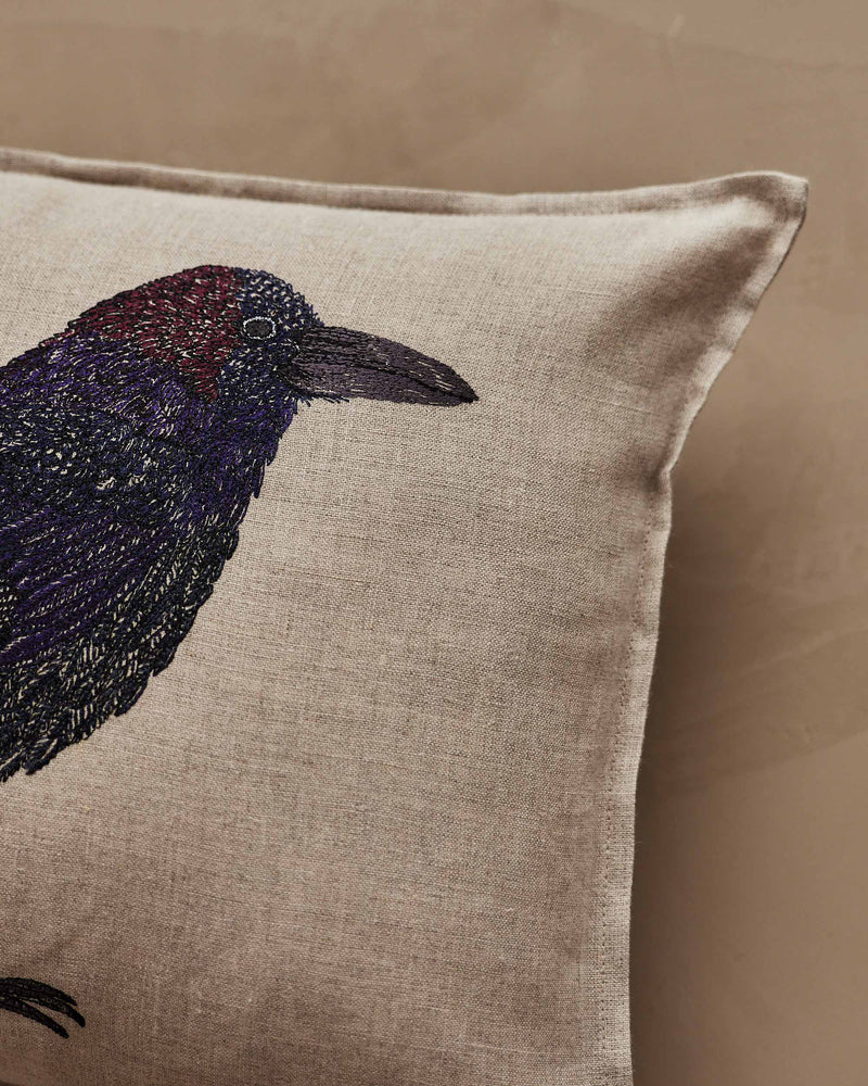 Coral & Tusk | Blackbird with Acorn Pillow: Linen cushion featuring an embroidered crow motif with vibrant feathers and an acorn, symbolizing new beginnings.