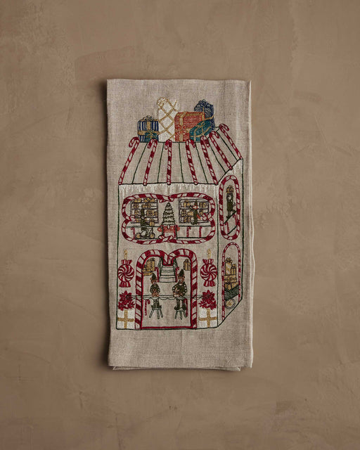 Coral & Tusk | Toy Workshop Tea Towel featuring embroidered whimsical gingerbread house scene with elves, candy accents, and gifts, perfect for a festive kitchen decor.