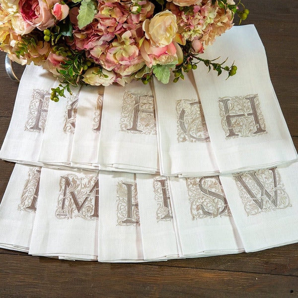 Crown Linen Designs | Monogram Linen Towel - R elegantly displayed beside a floral bouquet, showcasing its embroidered detail, perfect for elevating kitchen or bathroom decor.