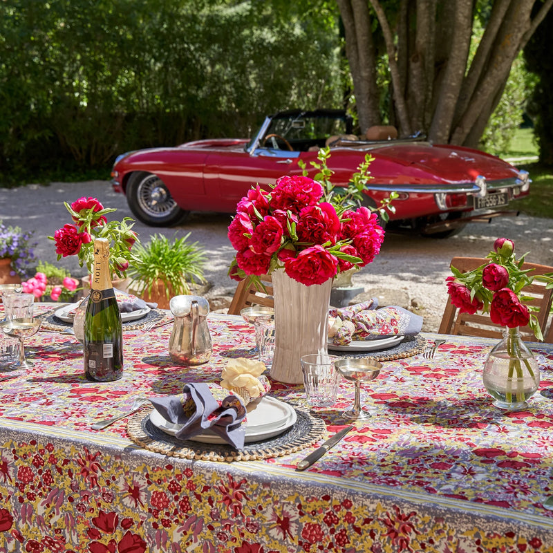 Caravan Home | 59 x 86 Red & Grey Tablecloth elegantly drapes a table adorned with plates and flowers, showcasing its vibrant, handprinted design inspired by Southern France gardens.