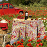 Caravan Home 71 x 71 Red & Grey Tablecloth elegantly draped on a floral-themed outdoor table, set amidst a field of flowers with wine and picnic items.